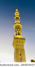 Close up low angle view of a beautiful illuminated minaret of Al-Masjid an-Nabawi towering against a clear evening sky during the umrah season