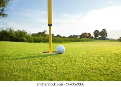 Close Up Low Angle View Of A Golf Ball On The Green Near The Hole On A Sunny Afternoon