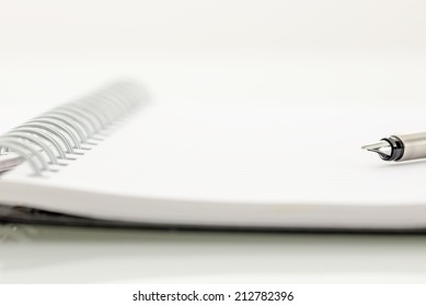 Close Up Low Angle View Of The Nib Of An Open Fountain Pen On An Open Spiral Bound Notebook With Blank White Spaces And Copyspace For Your Text Or Handwriting, Shallow Dof.