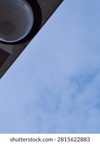Close up low angle view of a round outdoor light globe fixture against a blue sky
