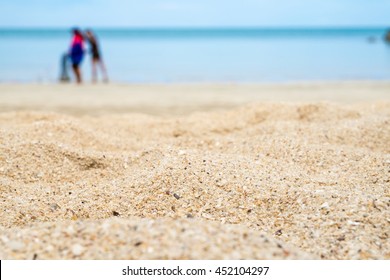 Close Up Low Angle View Of Sand Beach With Blur Sea And People At Background.