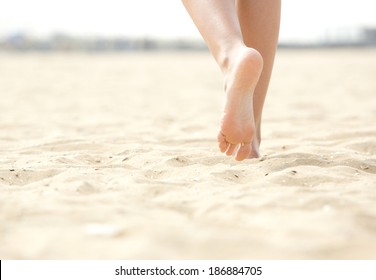 Close up low angle woman barefoot walking on beach