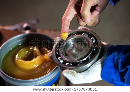 Close up of lubricant grease in hand Mechanic for putting into ball bearing in the industrial factory, Mechanic Industrial Concept