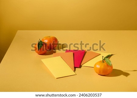 Close up of lucky money envelopes displayed on a yellow background with tangerines. Space for display and design. New Year theme. Advertising scene.