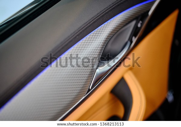 Close up of luxury car door panel. Interior of
prestige modern sports sedan car. Brown perforarated leather
cockpit. Door handle and armrest with window control panel and lock
button. Selective focus.