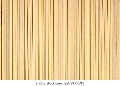 Close up macro background of raw long spaghetti strands arranged in a clean parallel geometric pattern