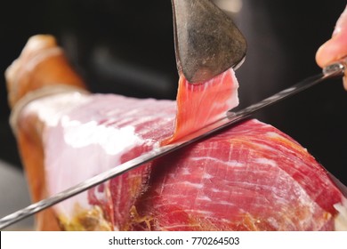 Close Up Macro Of A Chef Who Cuts A Slice Of Ham, Of Excellent Quality, With The Knife According To Tradition. Concept Of Ham, Food, Spain And Italy, Catering.