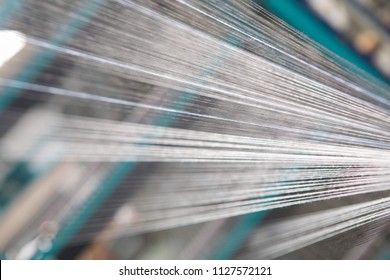 Close up macro detail of Yarn thread lines running in the weaving loom machine. Yarn bobbins making in a textile factory.