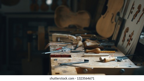 Close up macro of different violin maker work tools on workbench in a workshop of professional master artisan luthier.