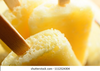 Close up (macro) of home made frozen yellow pineapple ice lollies (popsicles) with wooden stick handles.  - Powered by Shutterstock