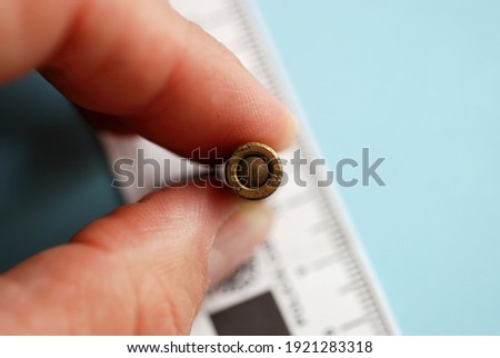 Close macro shot of an old unexploded bullet held by a hand, for police ballistics studies