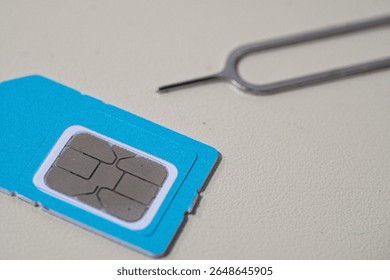 Close up macro of SIM card and SIM tray ejector tool. Perfect for tech blogs, smartphone repair articles, mobile tutorials, or telecommunications-related content