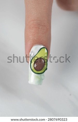 Close up macro of single fingernail decorated with a creative volumetric slice of avocado