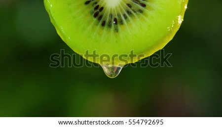 Close up or macro of a slice of kiwi, a drop of water falls in slow motion. The fruit gives off ffreshness and is filled with juice rich in vitamins and energy.Concept of fresh fruits, juices and kiwi