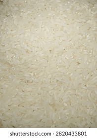 Close up macro texture of raw white rice grains. Uncooked staple food and agriculture product. White rice background for cooking, food, nutrition and healthy diet concept.