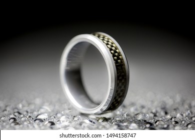 Close Up Macro View Of A Carbon Fiber And Tungsten Carbide Wedding Ring With A Black And Gray Background.