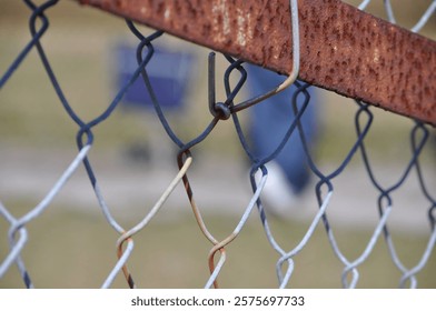 A close up macro view of a rusty chain link fence with a blurred background.