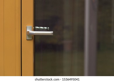 Close up macro view of silver door handle of yellow glass door. Building construction concept. 