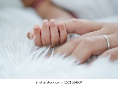Gros plan et l'accent principal sur la main du nouveau-né est de tenir le doigt de sa mère sur son lit.