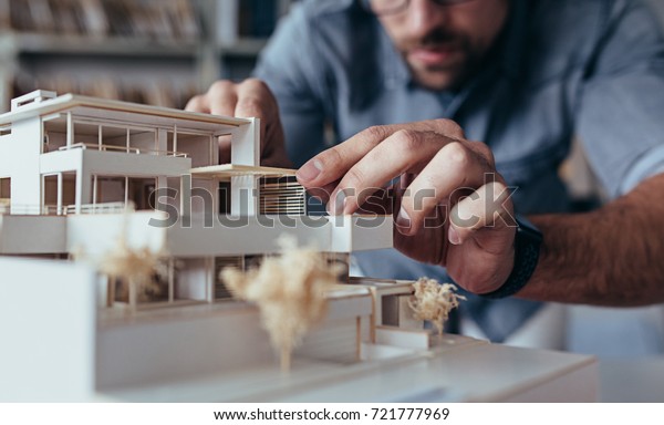 Close up of male architect hands making model house. Man architect working in the office.