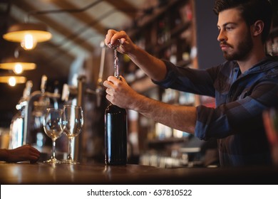 Close Up Of Male Bar Tender Opening A Bottle Of Wine At Bar Counter