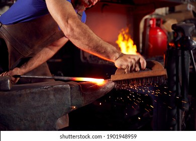 Close Up Of Male Blacksmith Using Wire Brush On Metalwork Resting On Anvil With Sparks - Powered by Shutterstock