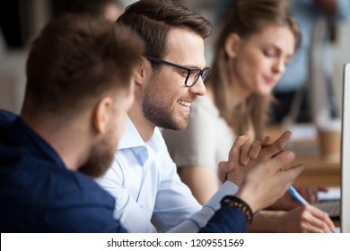 Close Up Of Male Colleagues Cooperating In Coworking Office Space Talking Laughing Together, Smiling Man Workers Chat At Workplace, Discussing Something Having Fun, Employees Joke While Working At Pc