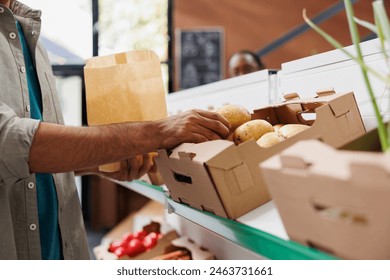 Close up of male customer choosing locally grown potatoes from shelf of eco friendly store. Detailed image of consumer selecting freshly harvested produce to cook healthy food recipe. - Powered by Shutterstock