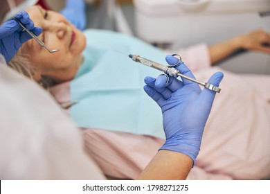 Close up of male dentist in blue medical gloves giving his patient anesthesia injection in dental clinic - Powered by Shutterstock