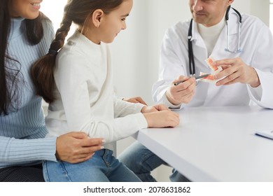 Close Up Of Male Dentist Talk With Mother And Small Daughter Patients At Consultation In Clinic. Man Doctor Consult Mom And Child About Oral Hygiene And Care. Dentistry, Medicine Concept.