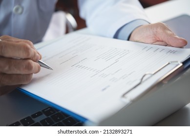 Close up of male doctor filling medical chart, checklist document, patient's information on clipboard. Doctor writing, signing on health insurance document in hospital, healthcare and medicine concept