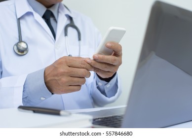 Close Up Male Doctor Or Medical Student Using Mobile Smart Phone Working On Laptop Computer In Hospital With Copy Space, Electronic Health Records System EHRs, Teleconference Or Telemedicine Concept.