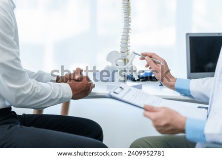 Close up male doctor and patient people in a medical office, spine model, possibly discussing spinal condition or syndrome with the patient. Stockfoto © 