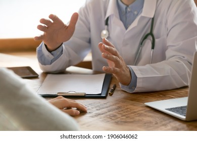 Close Up Of Male Doctor In White Medical Uniform Sit At Table In Hospital Talk Consult Female Patient Or Client. Confident Man GP Have Consultation With Woman In Clinic. Medicine, Healthcare Concept.