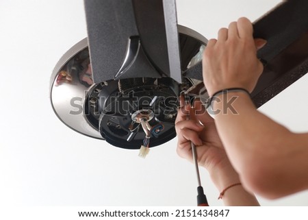 Close up a male electrician fixing and installing a ceiling fan in a house. Selective focus image.