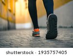 Close up of male feet walking during workout. Legs of man run in the city and jogging alone. Crocodile view of a runner doing sport activity in a deserted town. Closeup of running shoes stepping.