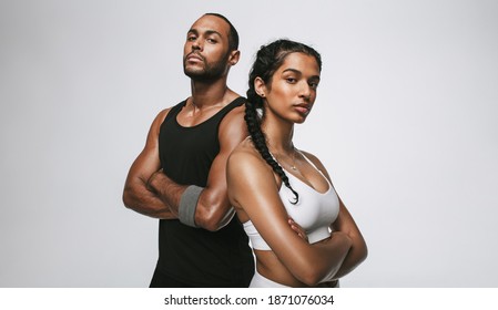 Close up of male and female athlete standing with arms crossed. Couple in fitness wear standing together at the gym. - Shutterstock ID 1871076034