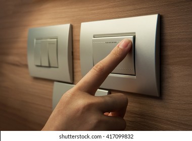 Close Up Of Male Finger Is Turn Off On Grey Button Of Light Switch Over Wood Wall At Home. Power, Energy, Saving Electrical. 