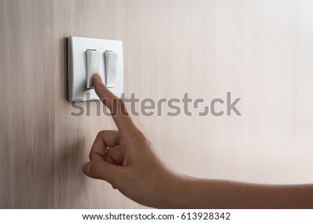 Close up of male finger is turn on or off on light switch with wood wall at home. Power, Energy, Saving Electrical. Copy space. 