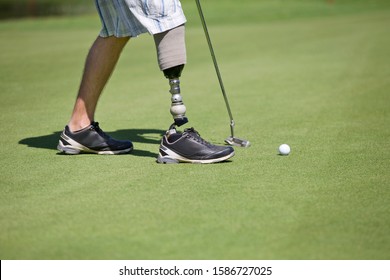 Close Up Of Male Golfer With Artificial Leg Putting Ball On Green