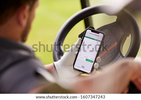 Close Up Of Male Golfer In Buggy Checking Score On Mobile Phone App