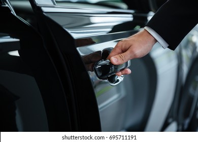 Close up of a male hand closing a car door at the dealership - Shutterstock ID 695711191