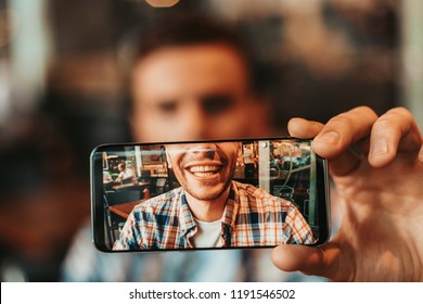 Close Up Male Hand Demonstrating Screen Of Phone With Picture Of Dude Mouth With Teeth. Glad Guy Having Fun With Gadget Concept