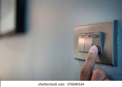 Close up male hand or fingers turn on or off on grey light switch with dark blue wall in the night time at home. Power, Energy, Safety, Saving Electrical. Copy space.  - Shutterstock ID 376040164