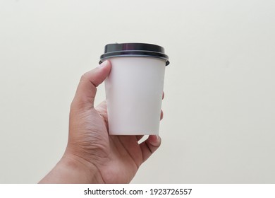 Close Up Of Male Hand Holding A Paper Cup Of Coffee Over The Gray Background