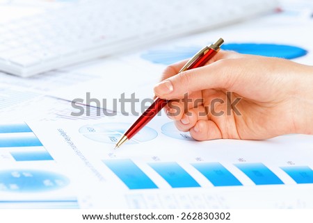 Close up of male hand holding pen and pointing at graphs
