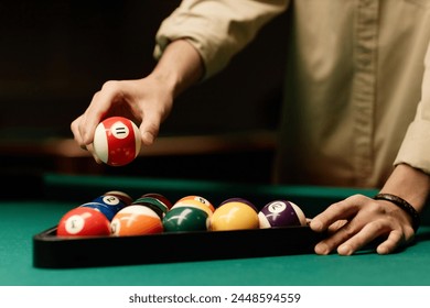 Close up of male hand holding red billiards ball over pool table in low light copy space - Powered by Shutterstock