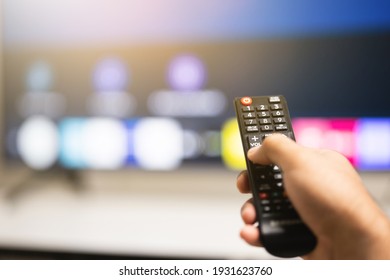 Close up male hand holding remote control pointing to change the programme television.