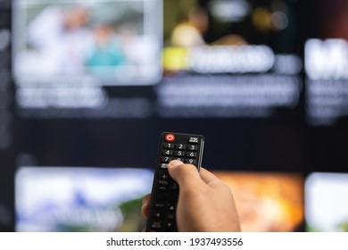 Close up male hand holding remote control pointing to change the programme television.