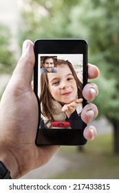 Close Up Of A Male Hand Holding A Smart Phone During A Video Call With His Daughter